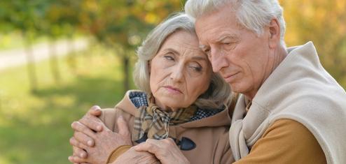 Ein älteres Paar umarmt sich liebevoll, es ist ein herbstlicher Park mit verschwommenem Hintergrund.